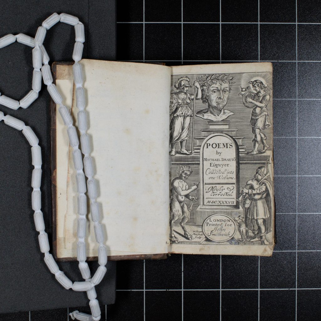 Michael Drayton’s Collected works, open to the title page. The page bears engraved illustrations of classical figures, with a portrait bust surmounting the title and author information.