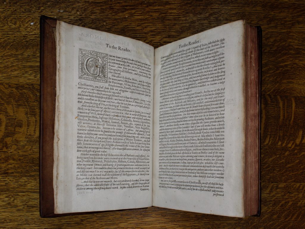 The book 'A Geographical Historie of Africa' mounted in a cradle so its pages are open. At the head of the pages is 'To the reader' in a large Roman typeface. Beneath, there is a large illustrated initial 'G' and the body of the text is densely printed in several paragraphs.
