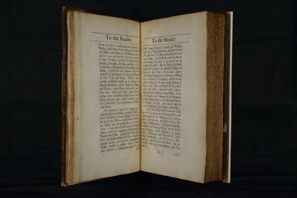 The book 'Pharmako-Basanos: Or, The Touch-Stone of Medicines' mounted in a cradle so the pages are open. The paper is off-white. The text is printed in black, in a large roman typeface. There are wide margins on the outer edges of the pages, often left so a reader could add their own annotations.